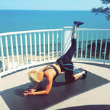 Woman exercising on a mat using Fitness Booty Bands to tone glutes and lower body by the ocean.