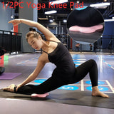 User demonstrating yoga stretches with a pink knee pad for joint protection in a fitness studio.